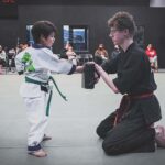 Child practicing martial arts with instructor.
